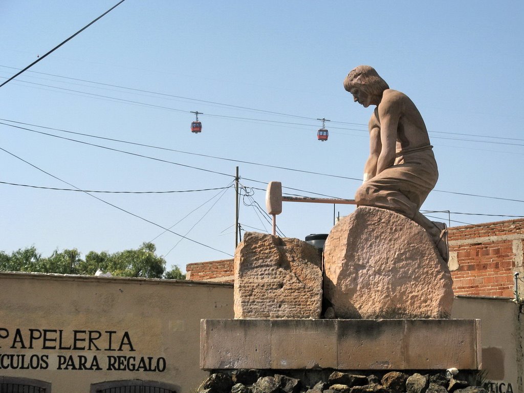 Two cablecars are crossing behind a statue of a worker with a hammer, Сомбререт