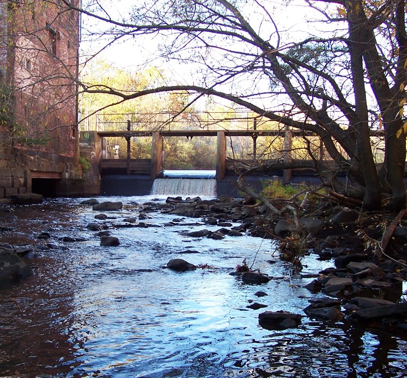 Standing on Adams St., looking upstream at the Walter Baker Dam on the Neponset River. This old dam prevents anadromous fish from migrating to their historical spawning grounds upstream. Learn about efforts to remove this dam that no longer holds floodwat, Милтон